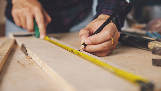 man measuring lumber